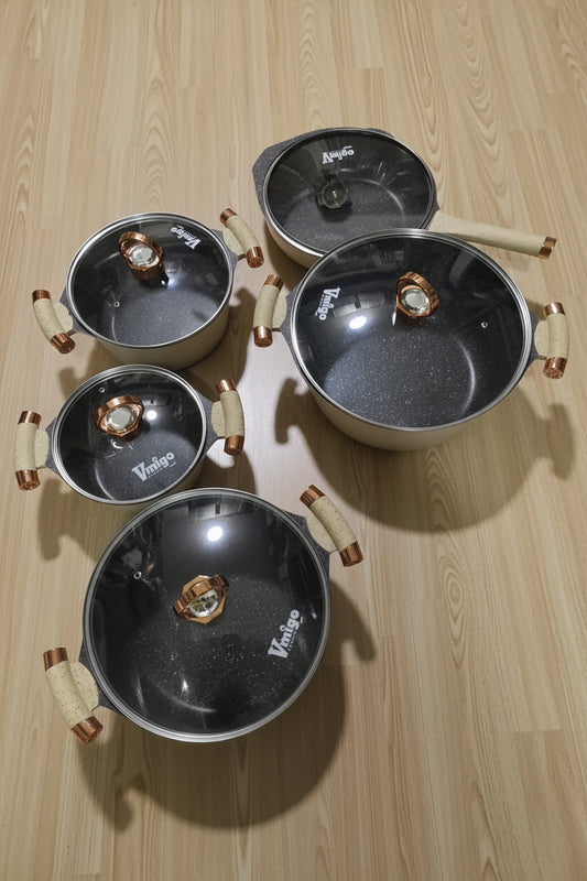 Set of metal cookware with handles on a tiled floor