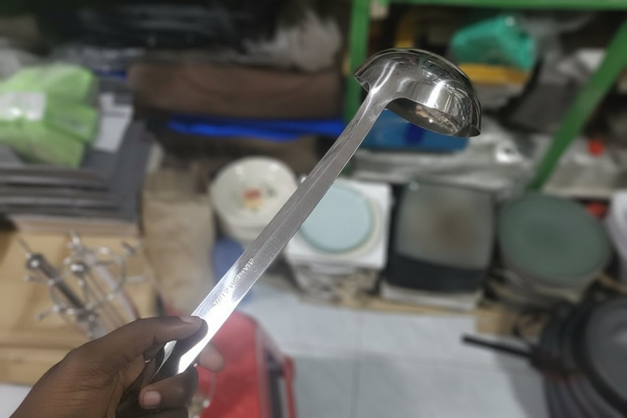 Metal ladle held above a cluttered store shelf with various items.