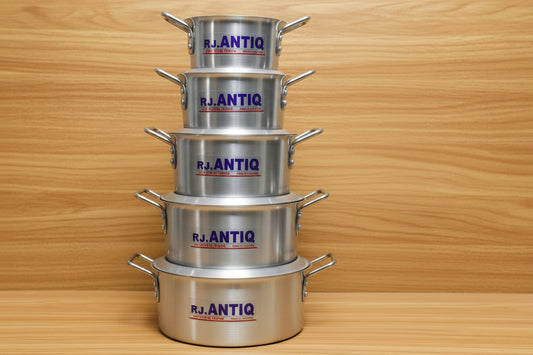Stacks of metal cookware with visible brand names on a wooden surface
