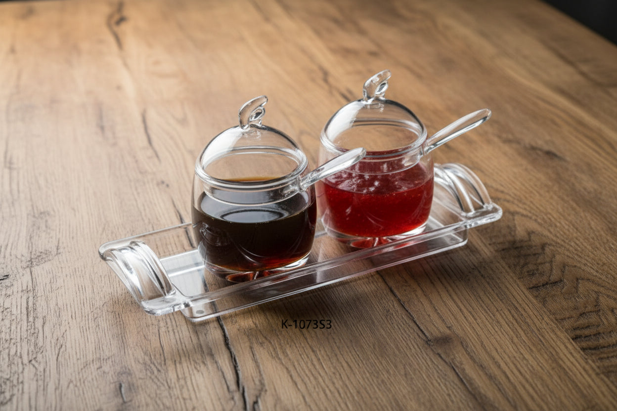 Set of two glass jars with lids on a clear tray, containing different colored liquids.
