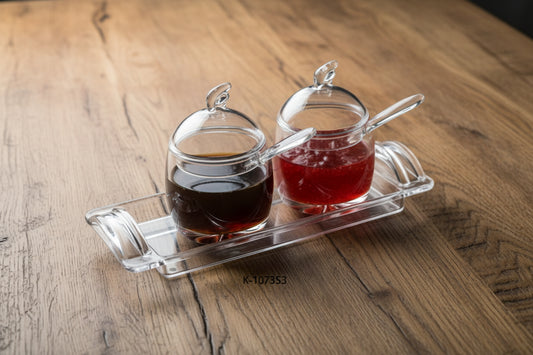 Set of two glass jars with lids on a clear tray, containing different colored liquids.
