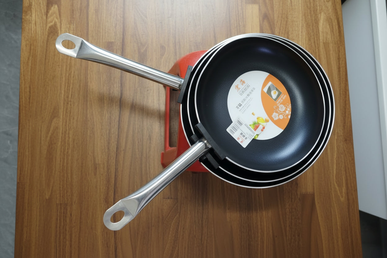 Set of frying pans with handles on a tiled floor