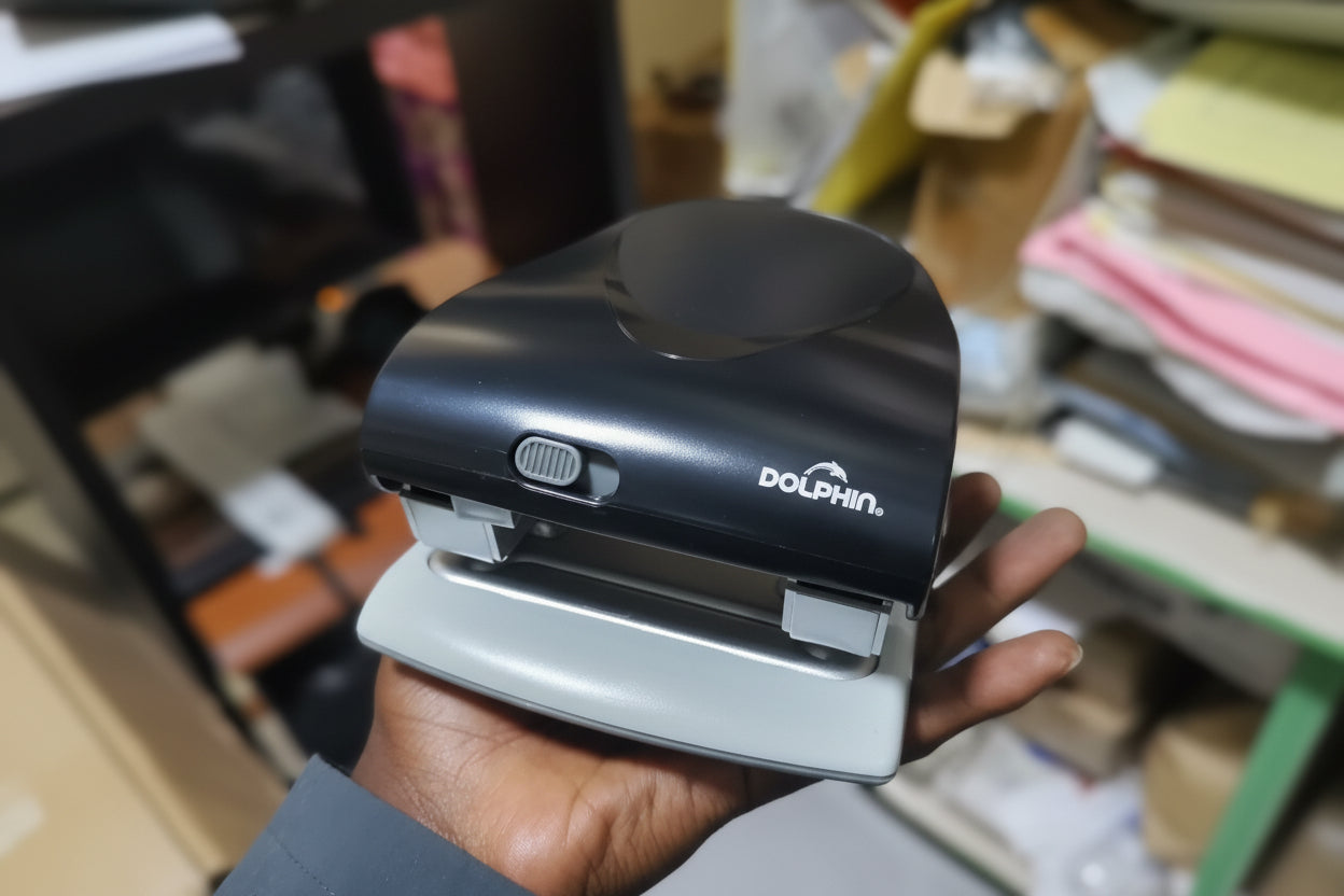 Hand holding a black and white device with 'Dolphin' branding in an indoor setting.