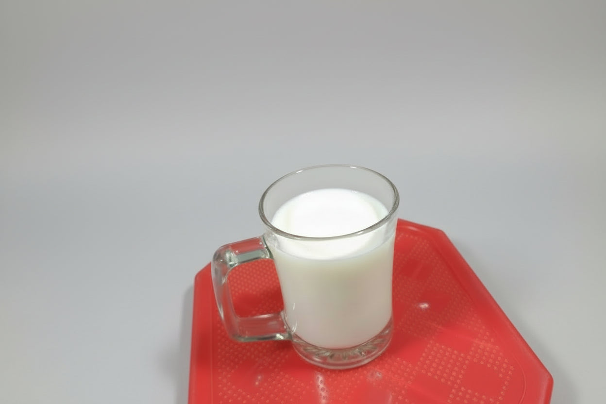 Clear glass mug on a red surface with various items in the background