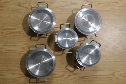 Five silver pots with lids on a tiled floor.