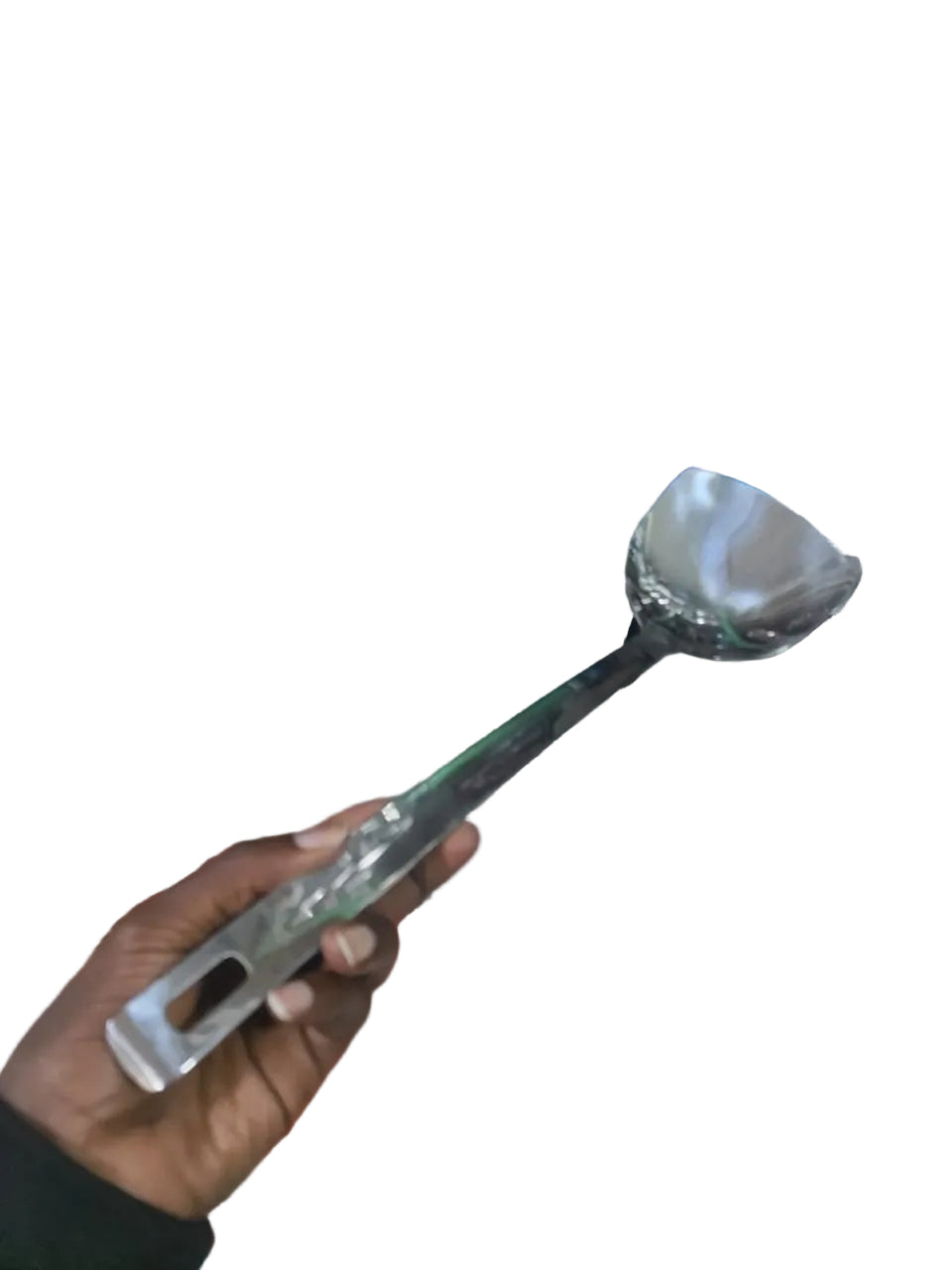 Person holding a large spoon in front of a cluttered shelf with various items.