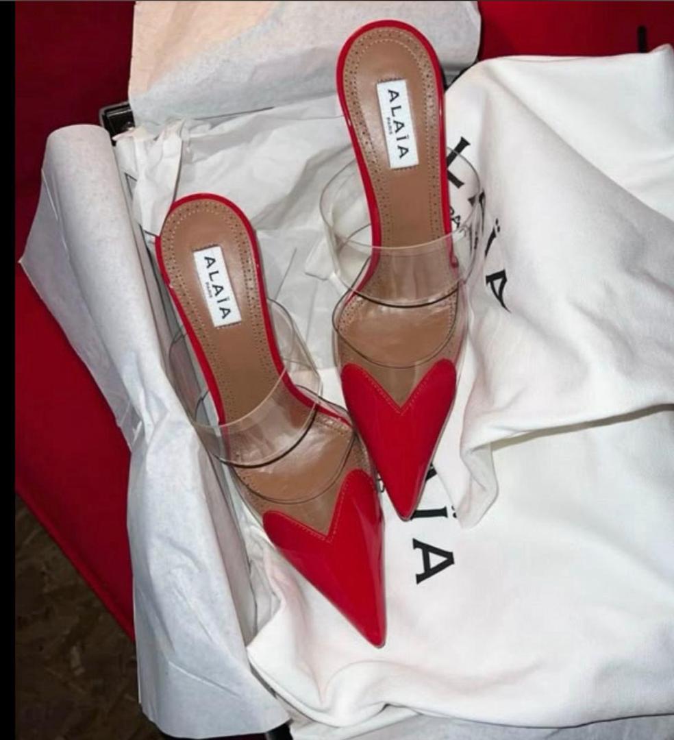 Red and clear shoes with heart design on a white fabric background