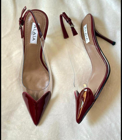 Pair of red high-heeled shoes with clear soles on a light background