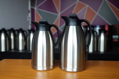 Two stainless steel vacuum flasks with black lids on a wooden surface, surrounded by 'Always' branded boxes.