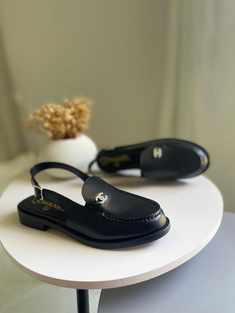 Black sandals with a brand logo on a white surface with a neutral background