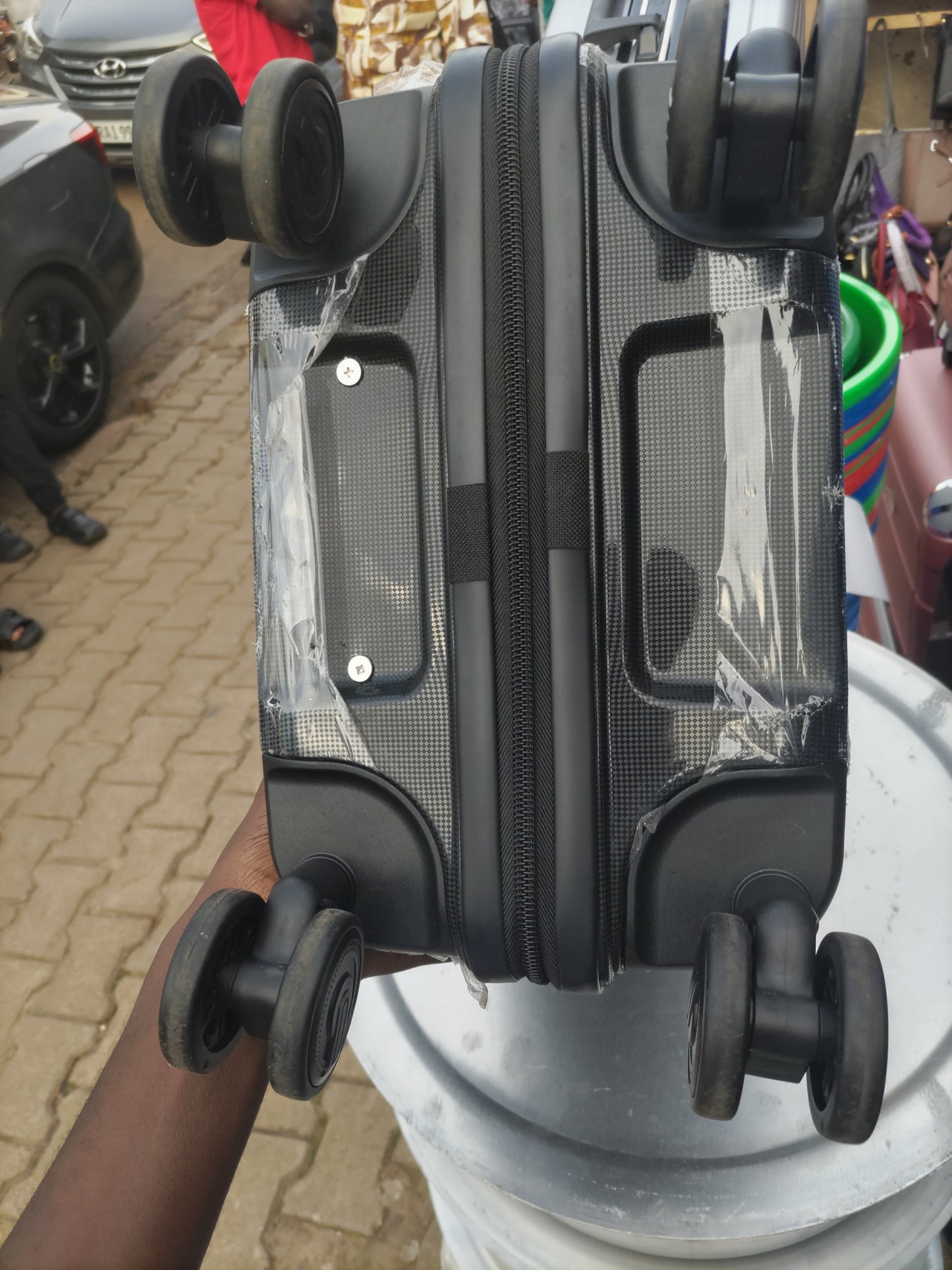 Black suitcase with wheels on a textured surface