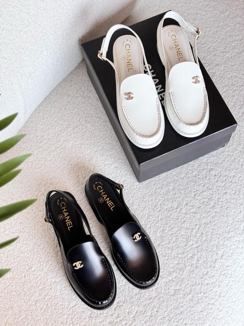 Black and white Chanel shoes with a box on a light surface.