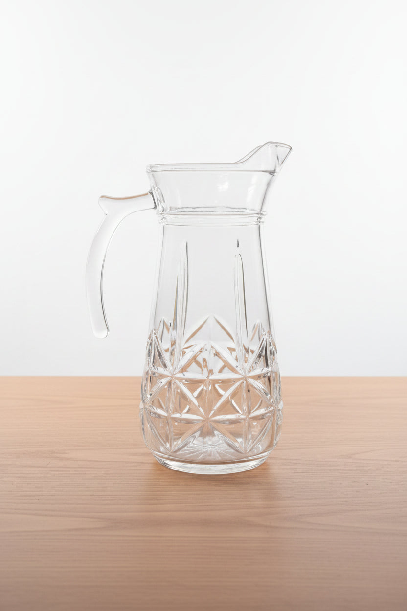 Clear glass pitcher with star patterns held in front of a store shelf.