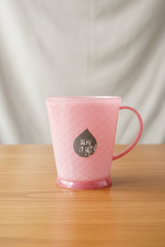 Pink mug with a brand logo held by a hand against a cluttered background
