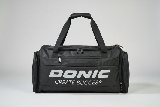 Black duffel bag with 'DONIC CREATE SUCCESS' text on a suitcase.