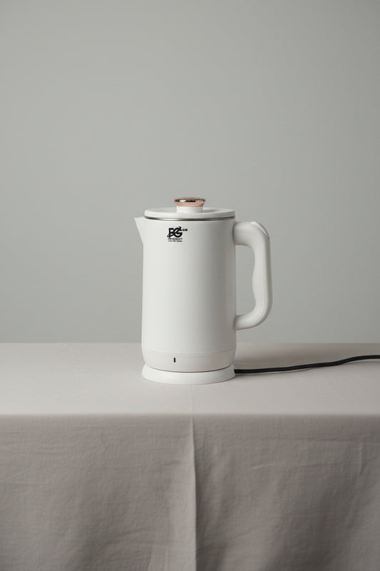 White electric kettle held by a hand with a blurred background