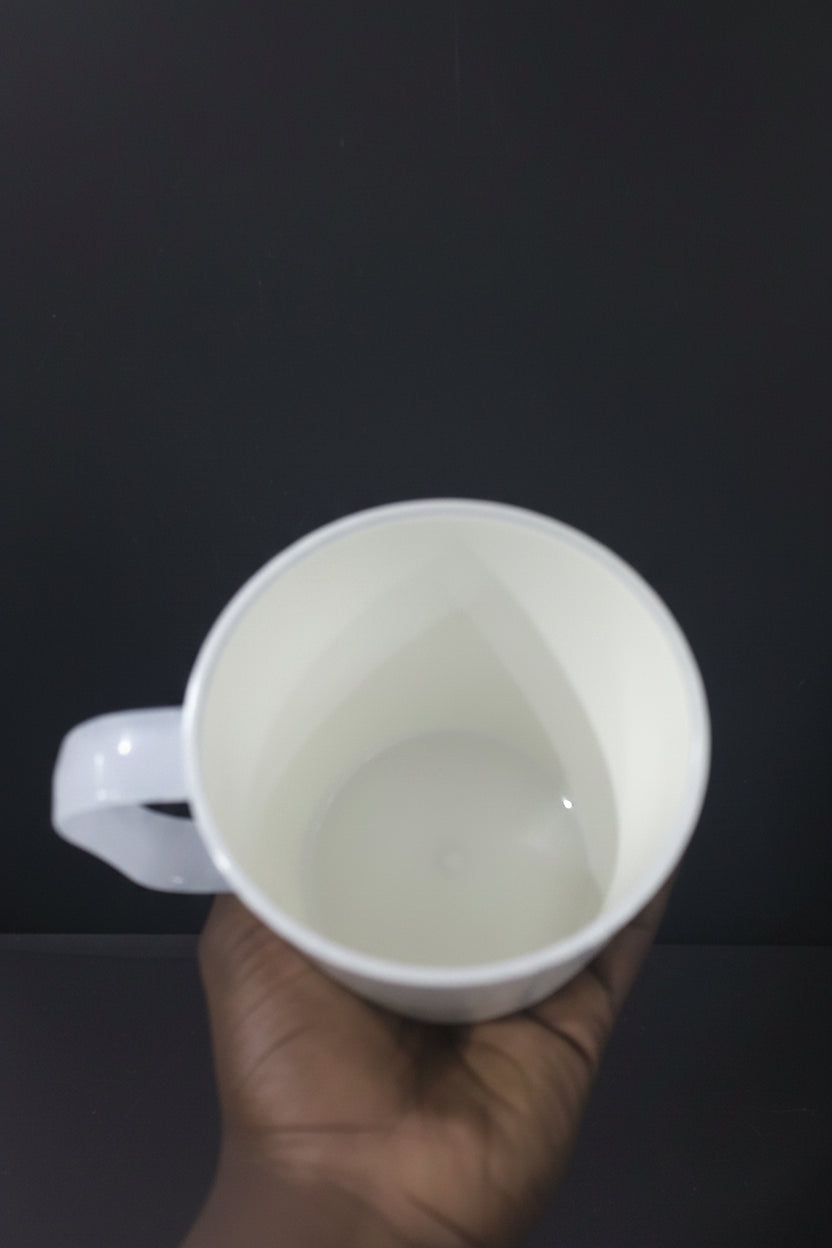 White mug held by a hand with a cluttered background of kitchen items