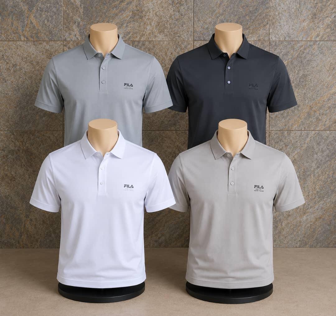 Four polo shirts in gray, black, white, and light gray on mannequins against a stone wall.