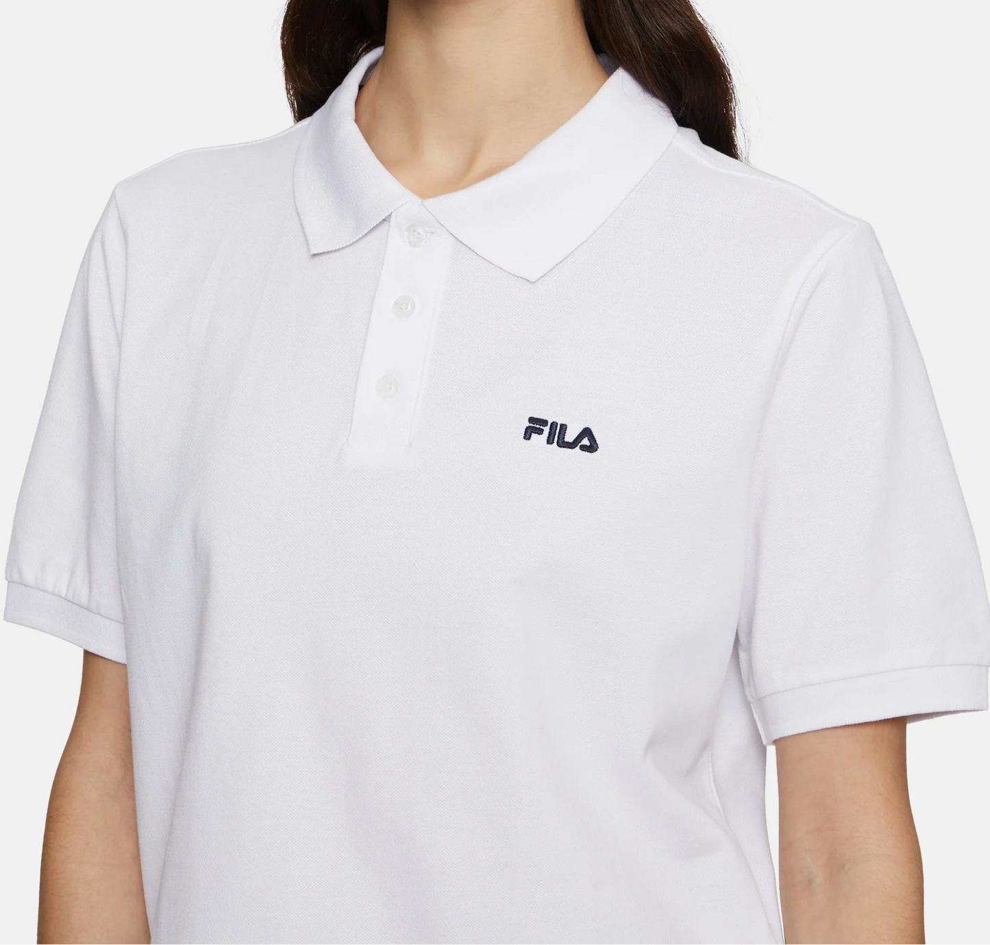 Woman wearing a white polo shirt with a Fila logo on a white background