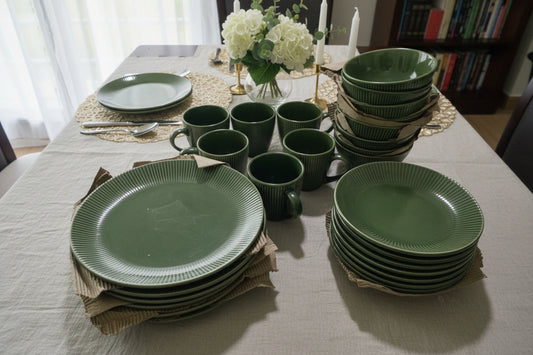 Collection of green ceramic plates and mugs on a white surface.