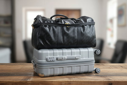 Black duffel bag with a yellow logo on a background of suitcases and shelves.
