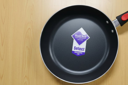 Black frying pan with a visible brand label on a wooden surface