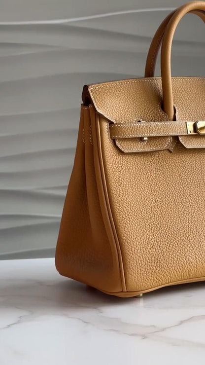 Brown leather handbag with gold hardware on a marble surface