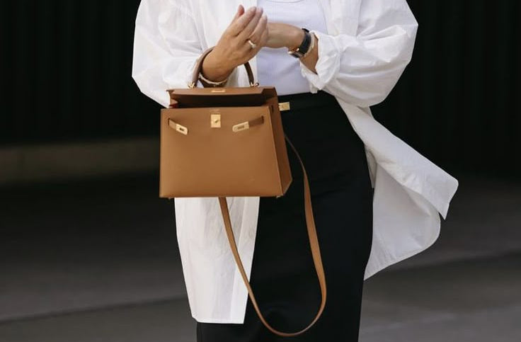Woman holding a brown handbag against a dark background