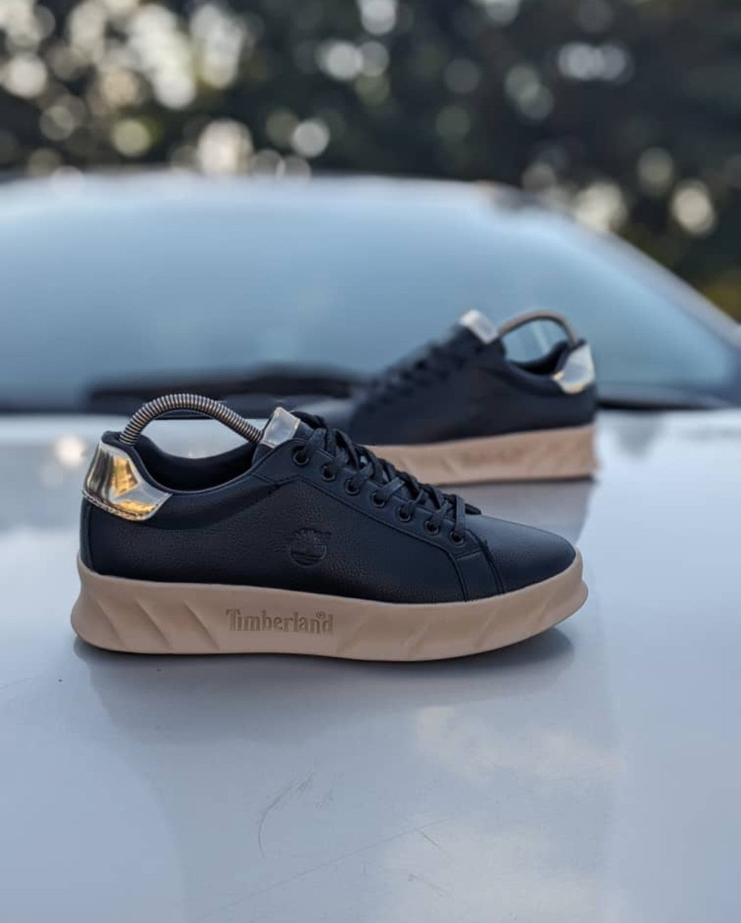 Black sneakers with tan soles on a car hood