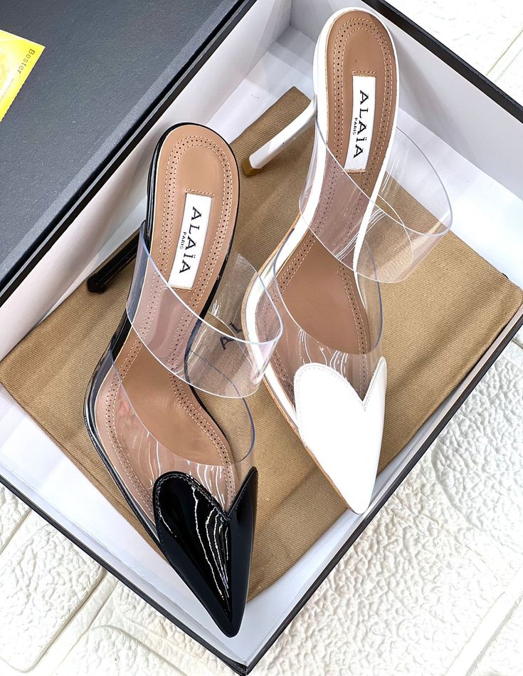 Black and clear high-heeled shoes with 'Alaia' branding on a white background