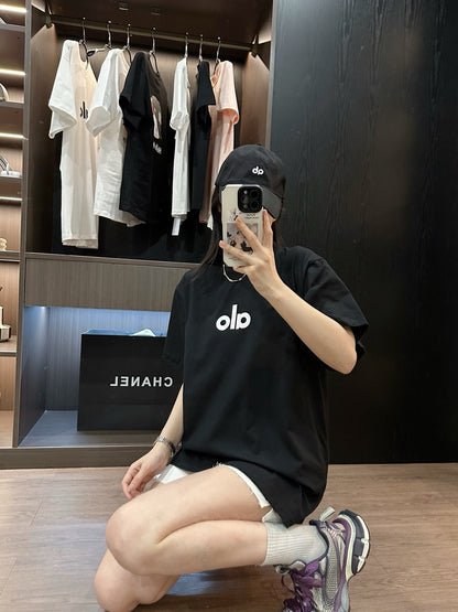 Person taking a mirror selfie wearing a black t-shirt with 'old' logo in a clothing store.