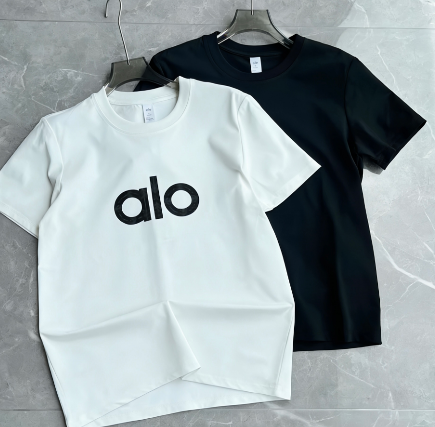 White and black t-shirts with 'alo' logo on a gray surface