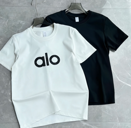 White and black t-shirts with 'alo' logo on a gray surface