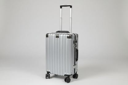 Silver suitcase on a stone pavement with various items in the background