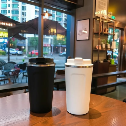 Two coffee tumblers, one black and one white with a city street background.