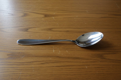Hand holding a spoon with a cluttered background of stacked white bowls and boxes.