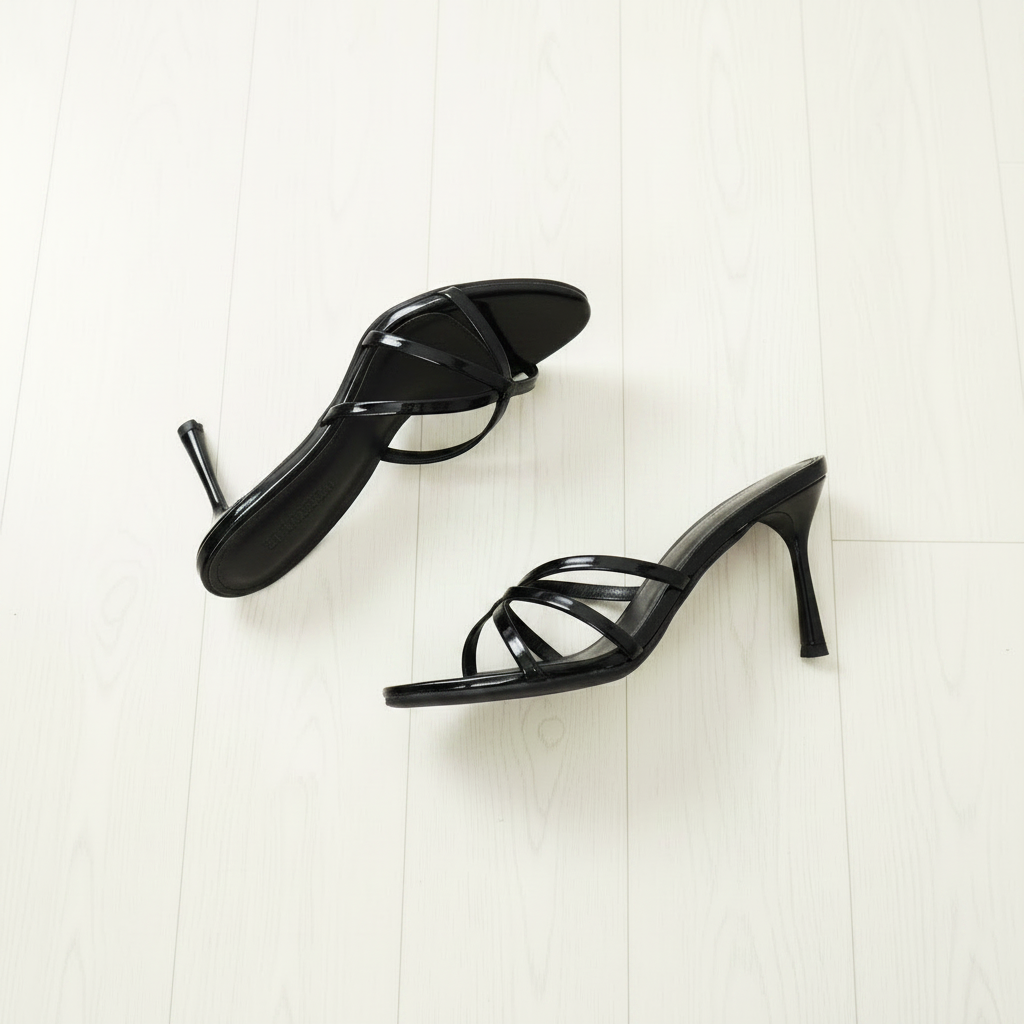 Black high-heeled sandals on a light wooden floor