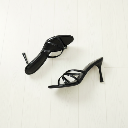Black high-heeled sandals on a light wooden floor