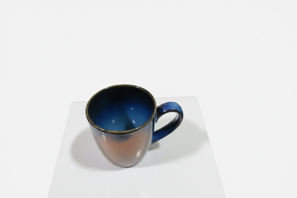 Blue mug on white surface with kitchen utensils in the background