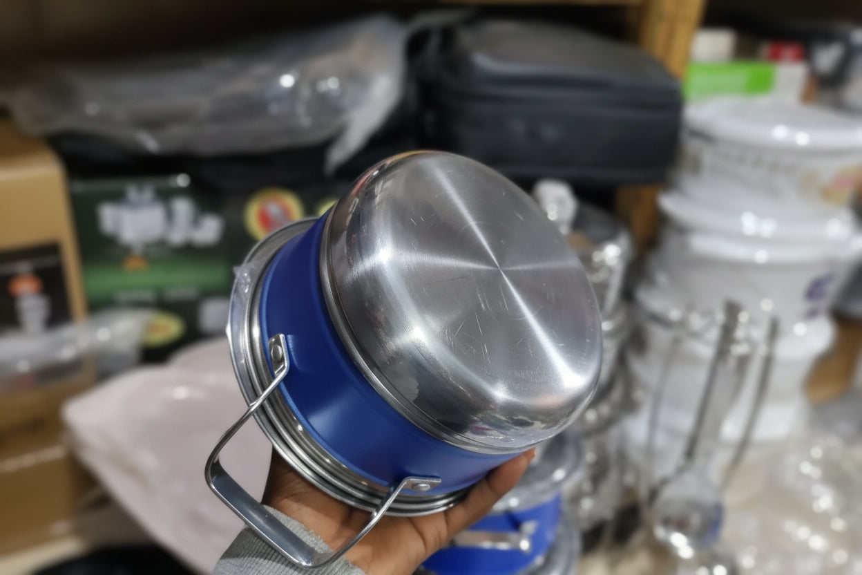 Person holding a blue and silver metal container with water bottles in the background