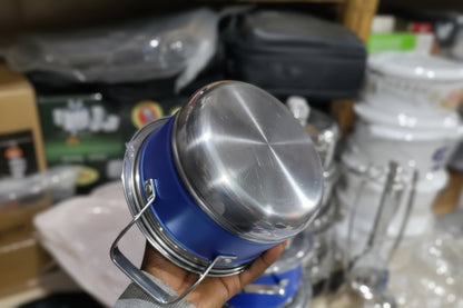 Person holding a blue and silver metal container with water bottles in the background