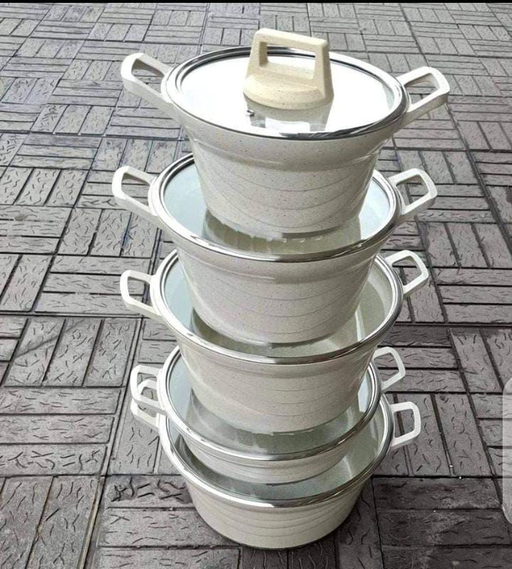 set of cooking pots and casseroles placed on the ground 