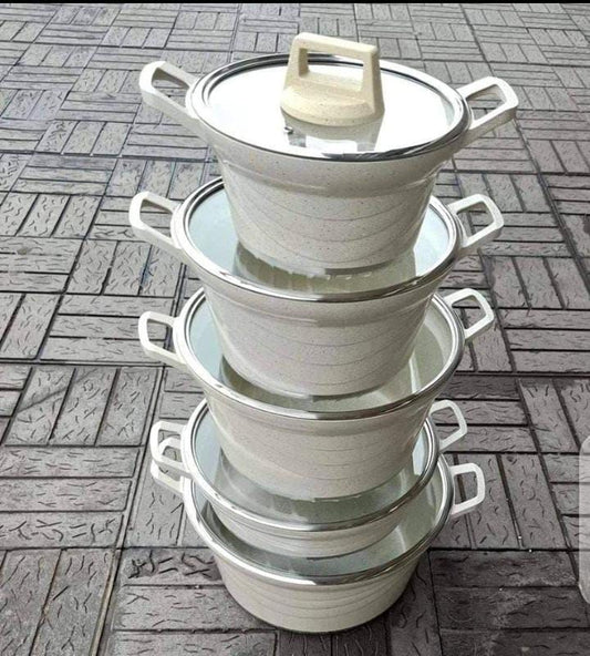 set of cooking pots and casseroles placed on the ground 
