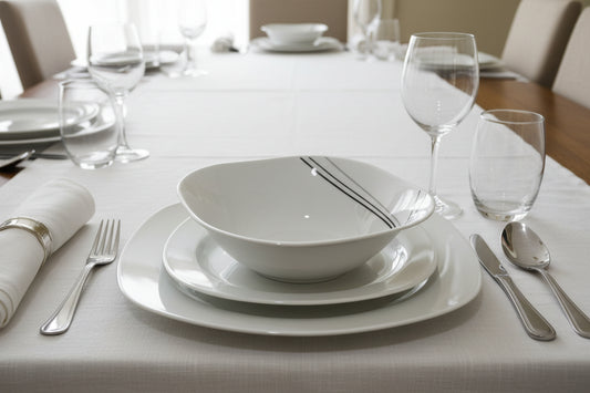White ceramic plate with black lines held in front of a display of similar plates.