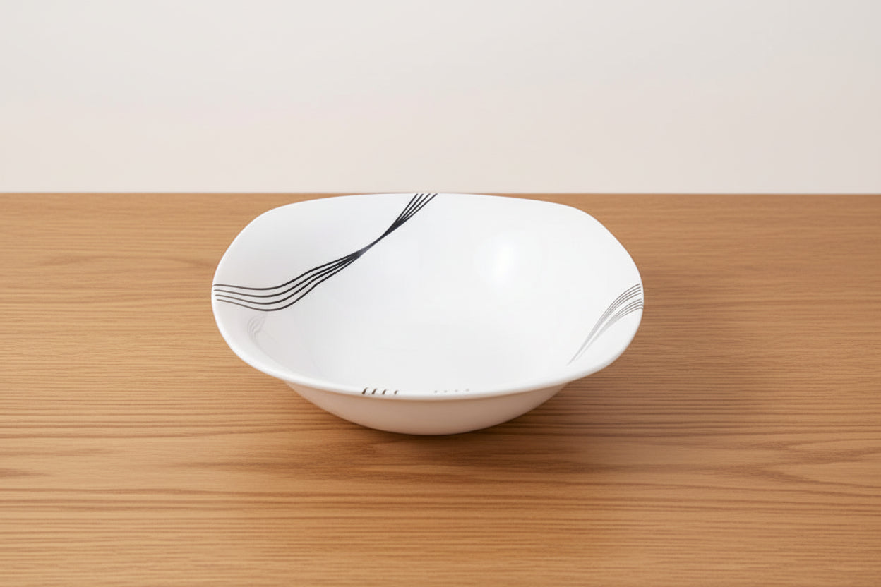 White ceramic bowl with black abstract design on a light beige background