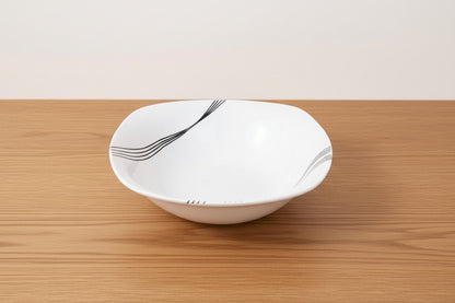 White ceramic bowl with black abstract design on a light beige background