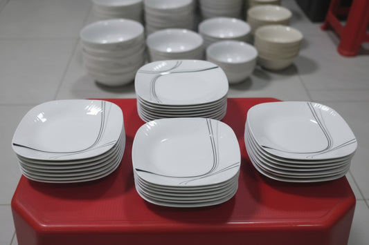 Stack of white ceramic plates on a red stool with a blurred background