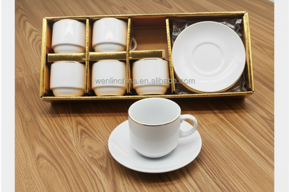 Set of white ceramic cups and saucers in a gold box on a white background