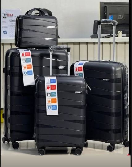 Set of black suitcases with travel stickers on a gray floor.
