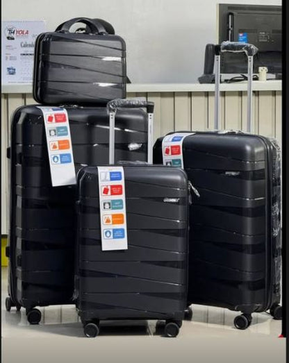 Set of black suitcases with travel stickers on a gray floor.